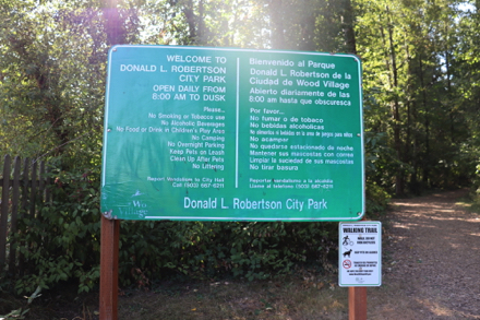 Welcome sign at the entrance to Donald L Robertson City Park includes hours of operation and park rules in English and Spanish
